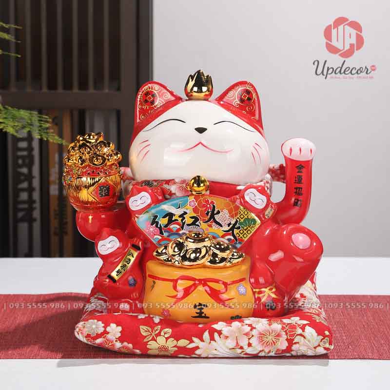 Mèo Thần Tài Vẫy Tay Nhật Bản Maneki Neko Mã UP019 Gương mặt mèo nằm ở trung tâm, trắng sáng và rất mềm. Đôi mắt cong nhẹ, miệng cười mảnh, hai bên má có vài nét râu đỏ. Biểu cảm của mèo không quá nghịch, cũng không nghiêm