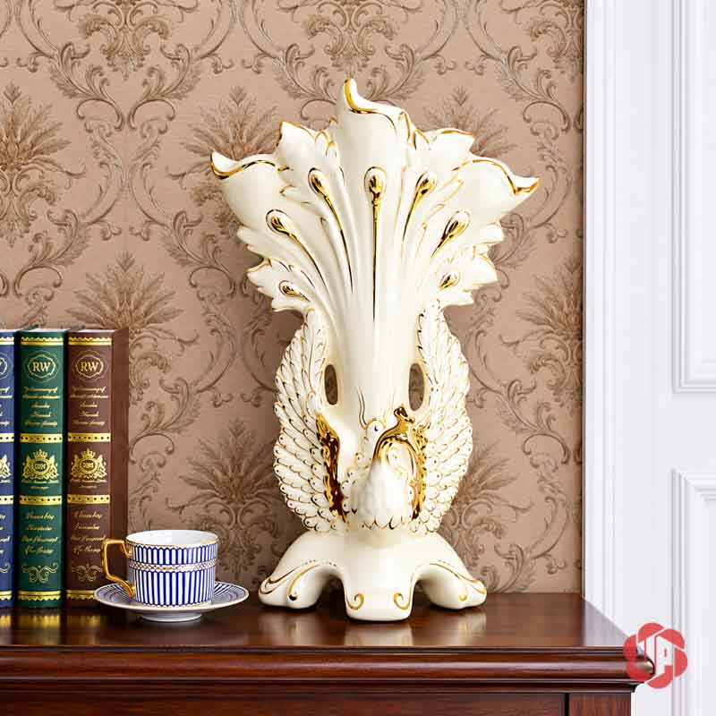 Bình Hoa Gốm Sứ Chim Công Trắng Viền Vàng Trang Trí Phòng Khách BG027 Bình hoa gốm sứ chim công trắng viền vàng trưng bày trên tủ gỗ cạnh sách và tách trà.