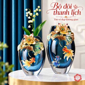Hai bình pha lê hoa sen và cá đặt trên bàn tròn, bình thấp cắm cành hoa trắng