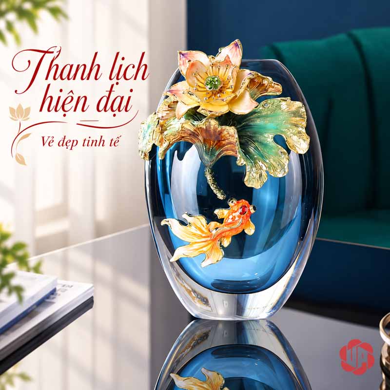 Bình Hoa Pha Lê Hoa Sen Và Cá Nghệ Thuật UPT19 Bình pha lê dáng thấp với hoa sen vàng xanh và cá màu cam trưng bày trước ghế nhung xanh