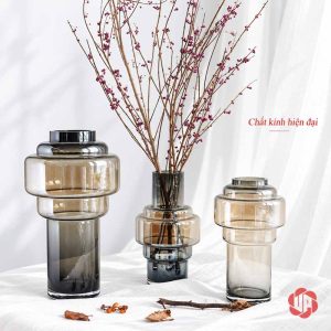 Ba mẫu lọ hoa thủy tinh màu khói với nhiều hình dáng và cành hoa trang trí