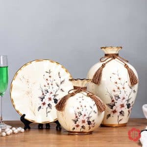 Bộ bình gốm sứ trắng kem họa tiết hoa cành gồm bình cao, bình tròn và đĩa trang trí.