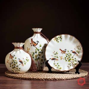 Bộ bình gốm sứ chim và hoa gồm hai bình và đĩa tròn trưng bày trên khay mây đan.
