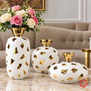 Bộ bình gốm sứ trắng bóng với họa tiết ánh kim vàng trang trí trên bàn đá