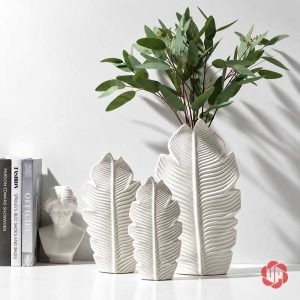 Ba bình lá gốm sứ trắng UP080 trưng bày cạnh sách và tượng trang trí