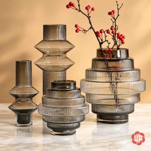 Bố cục lọ thủy tinh dáng tròn xếp tầng cùng bình cao và cành hoa đỏ