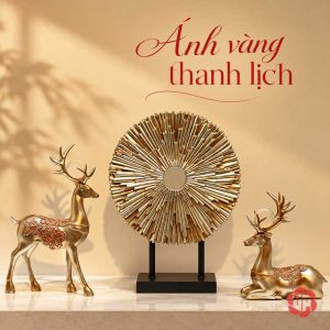 Bộ tượng hươu đứng và hươu nằm màu vàng cùng đĩa tròn nan tỏa đặt trên bàn màu kem