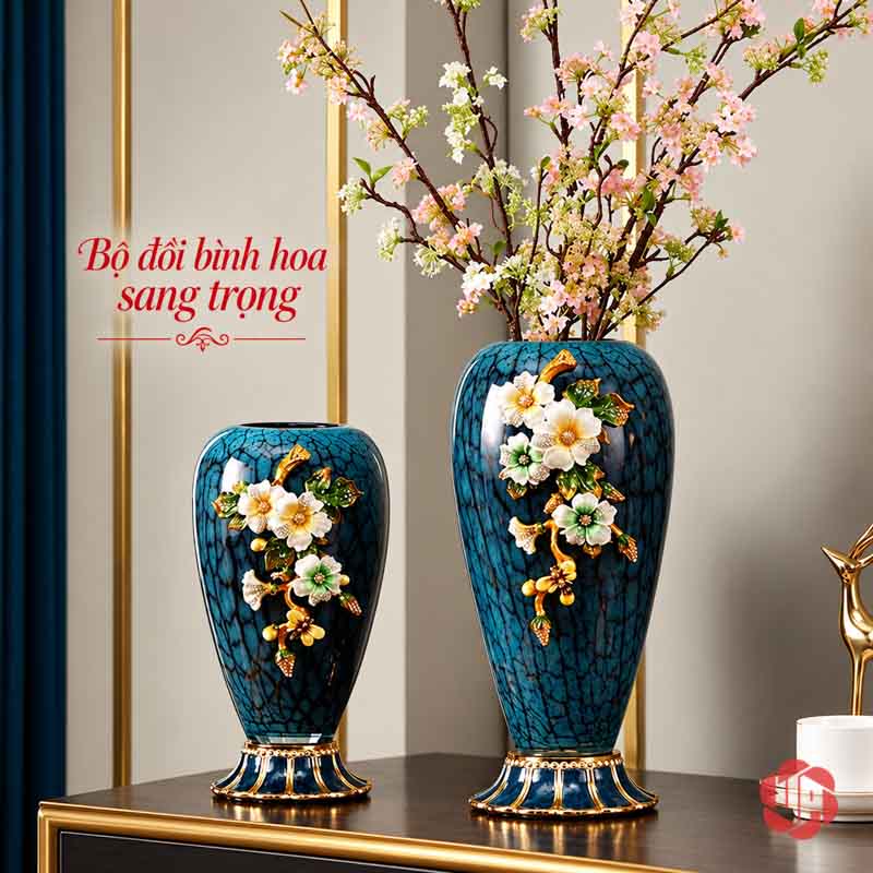 Bình Hoa Thủy Tinh Cao Cấp Xanh Ngọc Hoa Đắp Nổi UP003 Hai bình hoa xanh ngọc phối hoa trắng đắp nổi trên bàn với dòng chữ giới thiệu sản phẩm