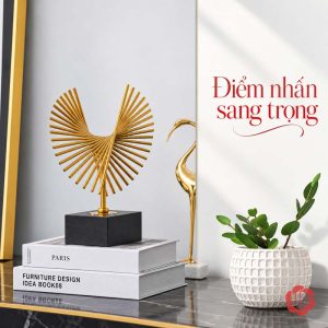 Decor phòng làm việc cánh chim bay đặt trên sách cạnh chậu cây xanh