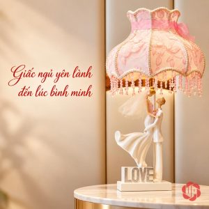 Đèn đôi tình nhân trên bàn tròn sáng, chao hồng có nơ và hạt rủ