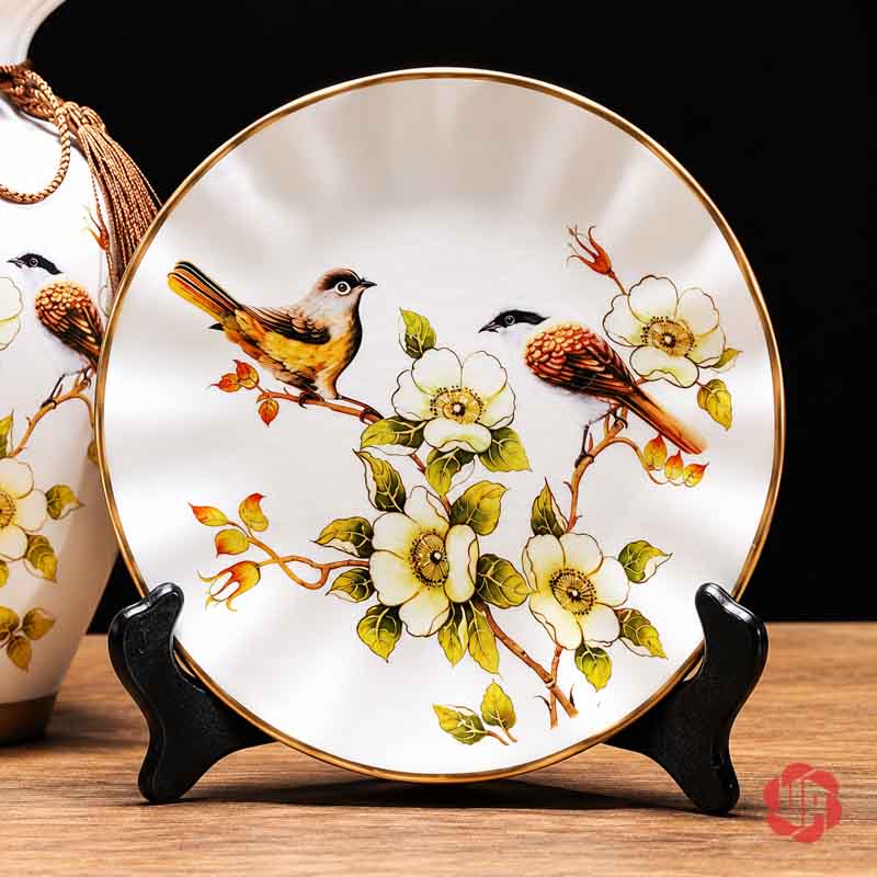 Bộ Bình Gốm Sứ Chim Và Hoa Trang Trí Phòng Khách 3 Món Đĩa gốm sứ tròn viền ánh vàng với họa tiết hai chú chim đậu trên cành hoa trắng.