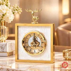 Đồng hồ hươu vàng dáng vuông nền trắng trên bàn cạnh hoa