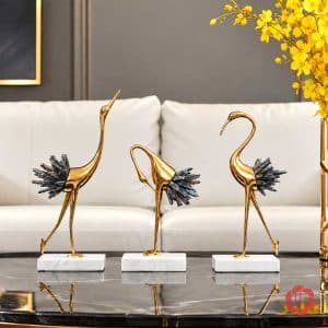 Ba tượng hồng hạc thân vàng, đuôi xanh xám trên bàn đá trước sofa