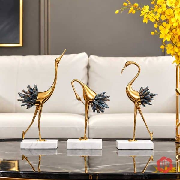 Ba tượng hồng hạc thân vàng, đuôi xanh xám trên bàn đá trước sofa