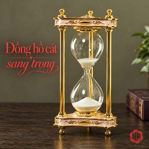 Đồng hồ cát trắng khung vàng có viền hoa văn trên bàn tối