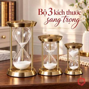Ba đồng hồ cát khung vàng cao thấp trên bàn gỗ