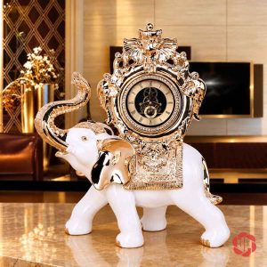 Toàn dáng đồng hồ voi trắng vàng đứng trên mặt bàn sáng