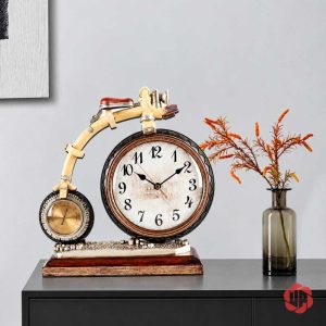 Đồng hồ xe đạp phong cách retro trên tủ tối cạnh bình lá