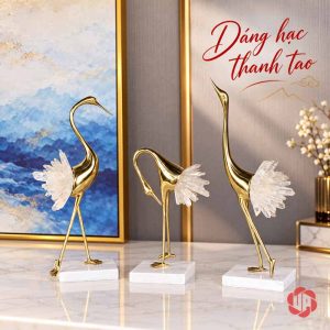 Ba tượng hồng hạc đuôi sáng màu, thân vàng trên đế trắng trước tranh xanh
