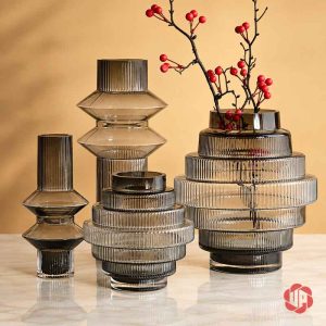 Bốn dáng lọ thủy tinh màu khói cùng cành hoa đỏ trong không gian ấm