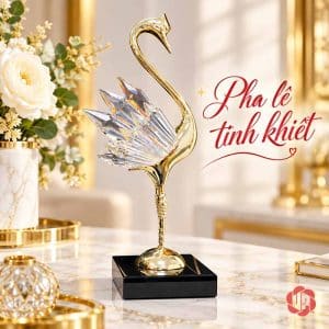 Một tượng thiên nga thân vàng, cánh trong suốt đứng trên chân đế đen
