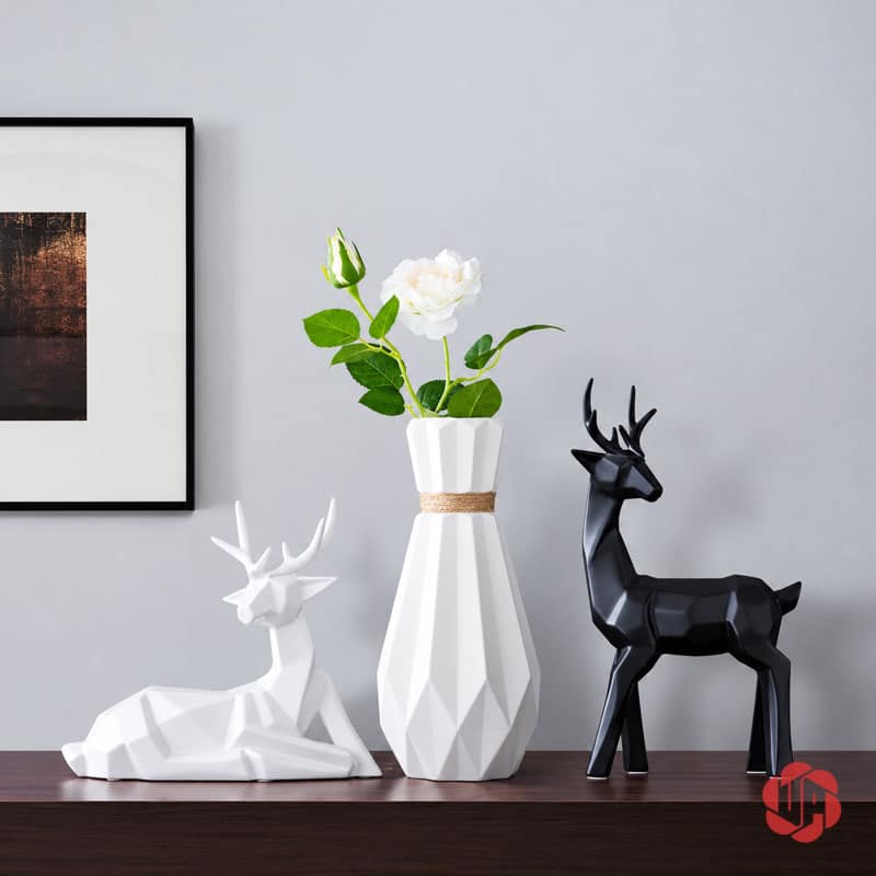 Bộ Tượng Hươu Decor Và Bình Hoa Sứ 3 Món Trang Trí Phòng Khách BG036 Tượng hươu trắng nằm cạnh bình hoa đa giác và tượng hươu đen đứng trên tủ gỗ.