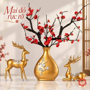 Bình màu vàng cắm hoa đỏ ở giữa hươu đứng và hươu nằm